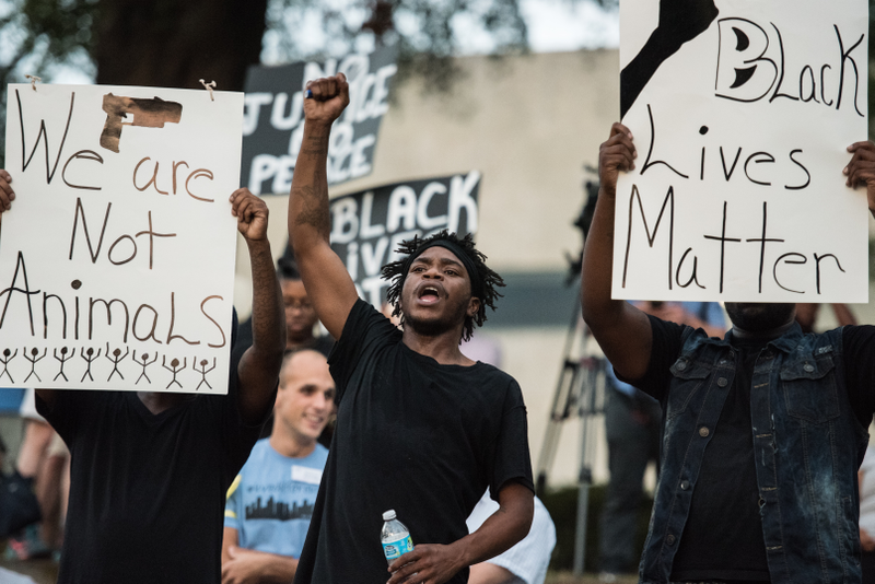 A young man raises his fist as he and others participate in a protest at Marshall Park in Charlotte, N.C., on Sept. 21, 2016.Sean Rayford/Getty Images